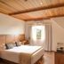 Hotel Le Renard in Campos do Jordão guest room with wood ceiling, double bed, and window view