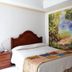 Hotel Bolivar Plaza room in Manizales with bed, nightstand and large forest mural