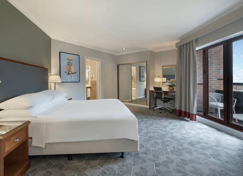 Delta Hotels by Marriott Waltham Abbey guest room with king bed, desk and balcony doors