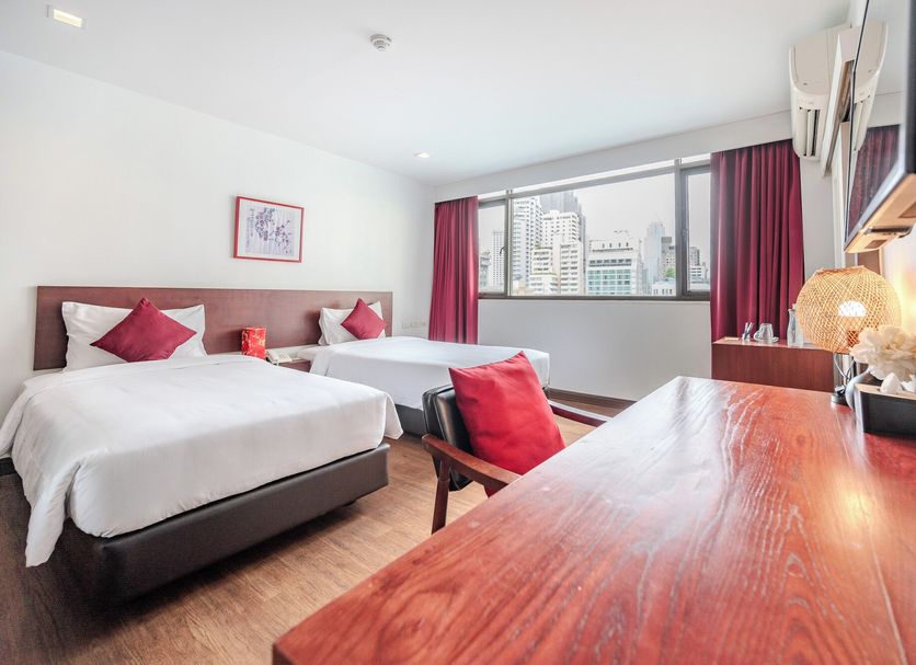 Ruamchitt Plaza Hotel in Bangkok guest room with two beds, desk, and city-view window