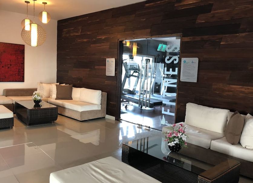 Suites Malecon Cancun lobby lounge in Cancún with sofas, glass tables, and gym entrance