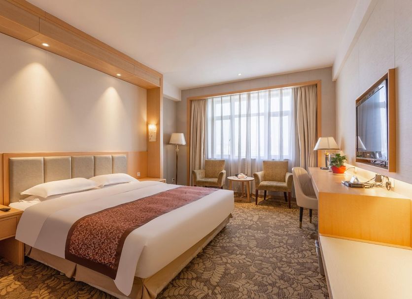 Li An Hotel in Hohhot: bright guest room with king bed, seating area, desk and large window