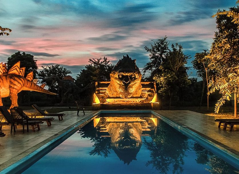 Yoko River Kwai Resort in Ban Lum Sum with a lit infinity pool reflecting a glowing owl sculpture at dusk