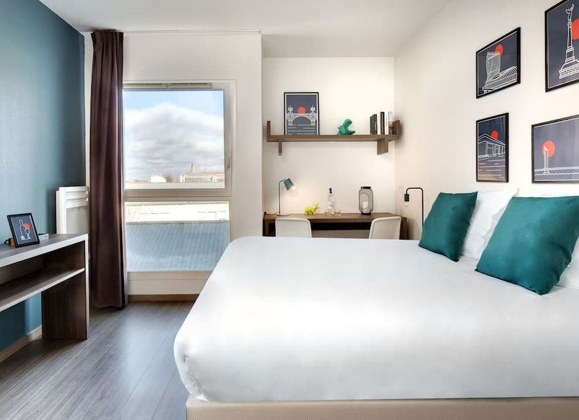Teneo Apparthotel Bordeaux Maritime guest room with king bed, desk and city view in Bordeaux