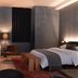 Mint House at 70 Pine, New York room with bed, desk, armchair, lamp and dark curtains