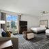Homewood Suites by Hilton New Braunfels room with two beds, sofa, and city view through window