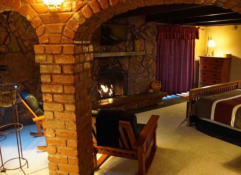 Lodge At Sedona room with stone fireplace, bed, and red curtains in Sedona