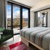 Moxy Asheville Downtown room with balcony view, striped bed, and green chair in Asheville