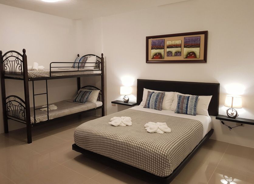 D´Gecko Hotel in Moalboal bedroom with double bed and bunk bed, bedside lamps, and framed wall art