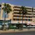 Ahla Tala Hotel in Aqaba exterior with balconies, palm trees, and streetfront shops