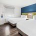 SureStay by Best Western Santa Monica room with two beds, blue accent wall, and window light