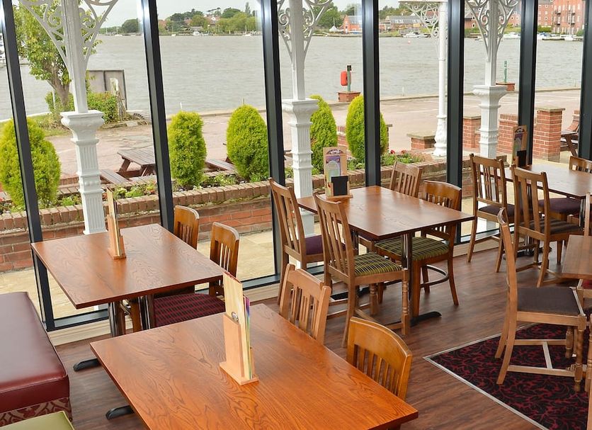 Wherry Hotel Lowestoft restaurant with waterfront view, wooden tables and chairs by large windows