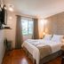 Pousada La Toscana room in Campos do Jordão with double bed, wood floor, and window view