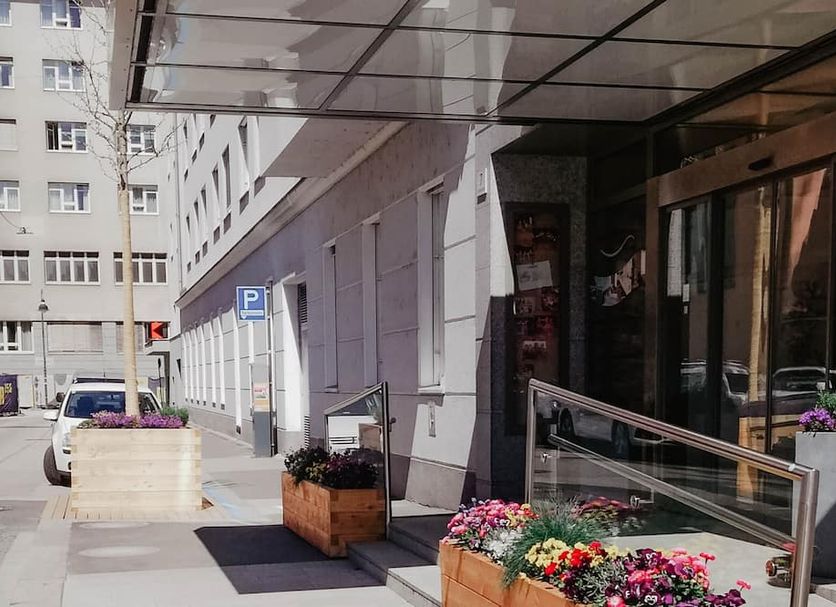 Stadtoase Kolping Hotel in Linz entrance with covered sidewalk and potted flowers