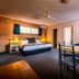 Park Beach Resort Motel in Coffs Harbour: hotel room with bed, dining table, sofa, brick accent wall and windows.