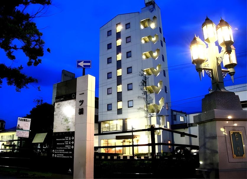 Hotel Ikedaya in Matsumoto, lit exterior at dusk with a tall tower and street lamps
