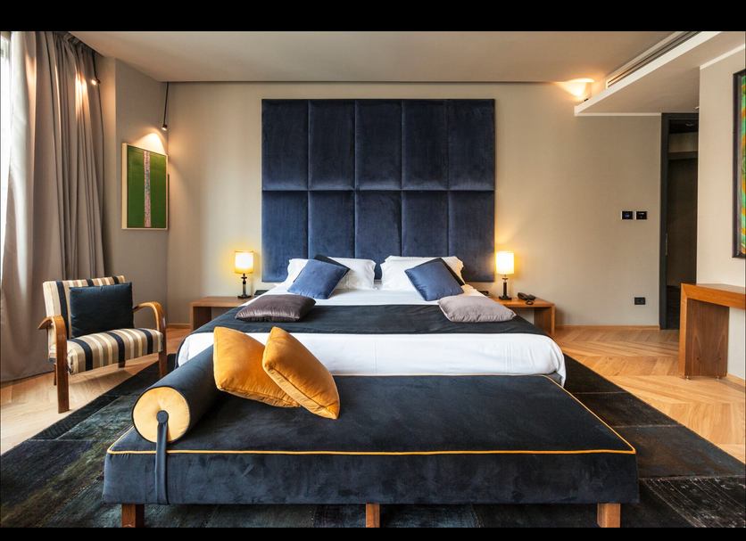 Triviho Hotel Rome guest room with king bed, chaise lounge, and bedside lamps