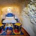 Kasbah Tizzarouine cave-style bedroom in Boumalne Dadès with a bed, rug, and seating stools
