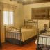 Las Iglesias Antigua guest room with two wrought-iron beds, tiled floor, and window curtains