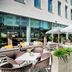 Leonardo Hotel Munich City South outdoor terrace with lounge seating, tables, umbrellas and greenery