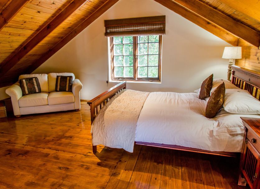 Le Manoir de Brendel Franschhoek attic bedroom with wooden beams, bed, loveseat and window