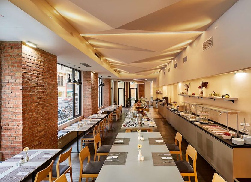 H+ Hotel Wien in Vienna breakfast buffet dining room with long tables and brick wall