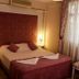 Dalyan Terrace Hotel room with double bed, folded towels, floral chair and sheer curtains in Dalyan