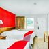 OYO Hotel Houston Southwest I-69 room with two beds, TV, desk, window, and red accent wall in Houston