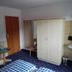 Pension Sonnalp Ortisei room with wardrobe, table, sink and blue checkered bedspread