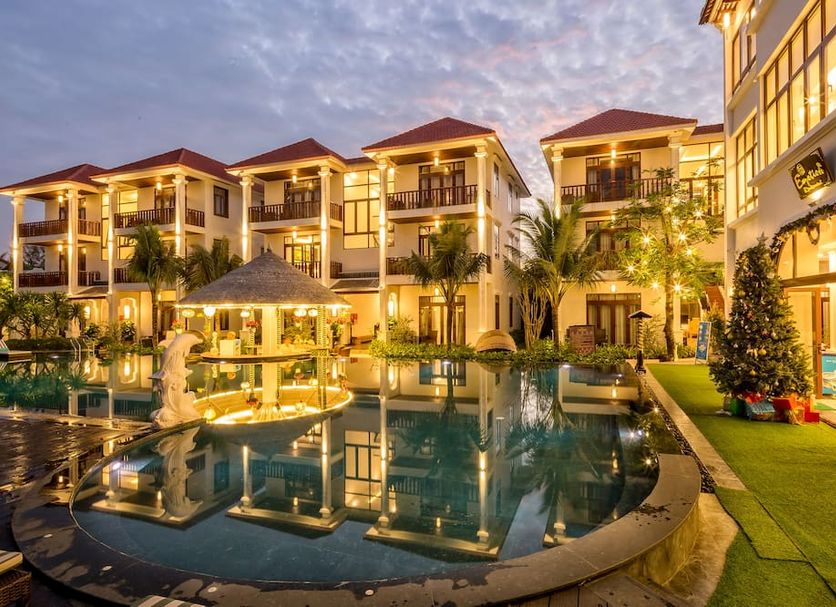 Hoi An Emotion Boutique Villa in Hoi An with a lit courtyard pool and palm-lined villas at dusk