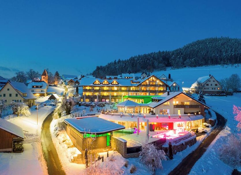 Hotel Heselbacher Hof in Baiersbronn at dusk, with colorful lit buildings on a snowy hillside