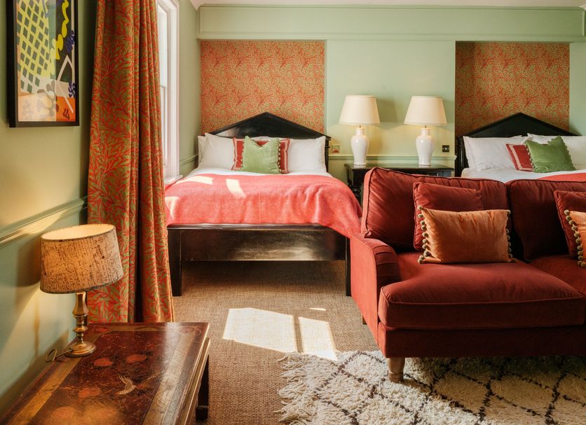 The Pembroke Arms, Salisbury: cozy guest room with twin beds, red sofa, lamps and window light