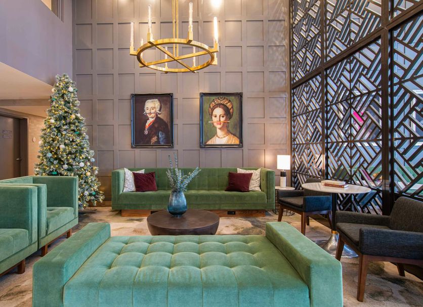Sandman Signature Ottawa Airport Hotel lobby with teal seating, holiday tree, and tall geometric window