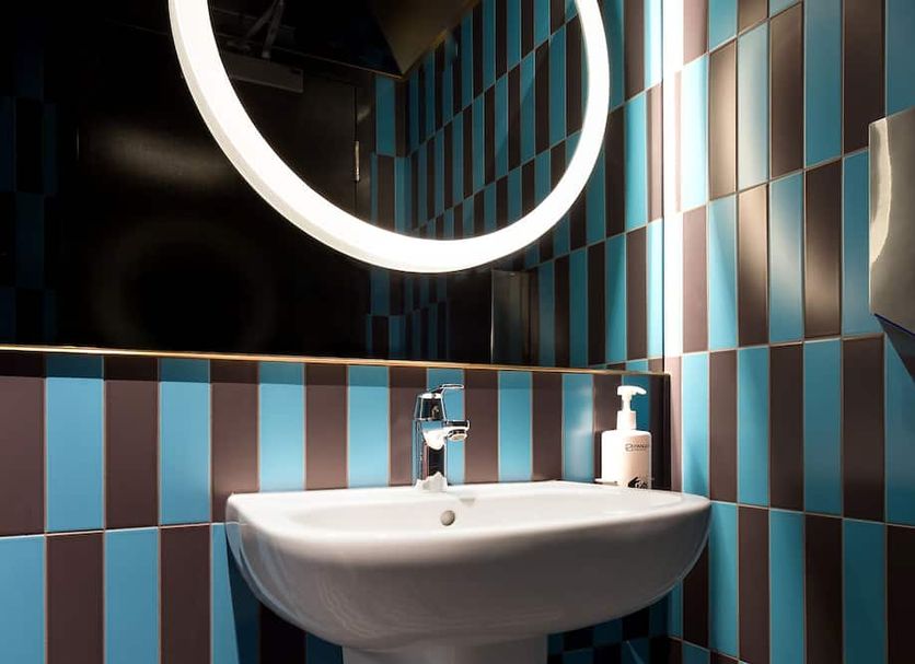 Pangea Pod Hotel in Whistler bathroom sink with round illuminated mirror and blue-brown tiled walls