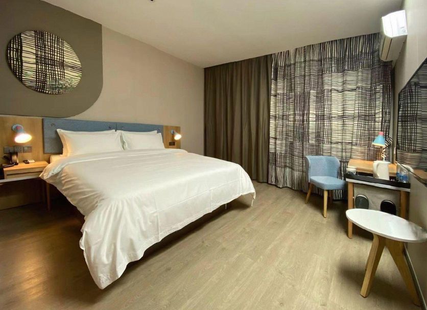 Home Inn Neo Shanghai Pudong Airport room with queen bed, desk, chair and large window curtains