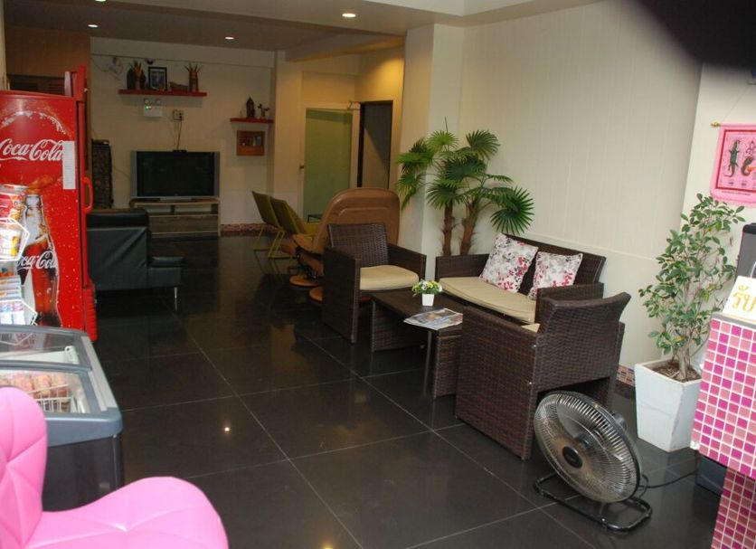 Keeree Boutique Hotel in Phetchaburi lobby seating area with wicker chairs, TV, and a Coca-Cola fridge
