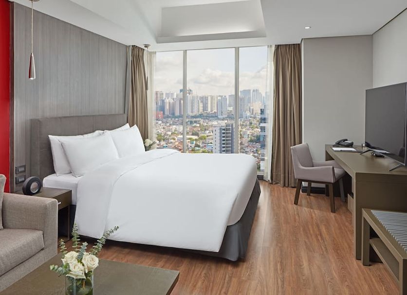 F1 Hotel Manila in Taguig guest room with king bed, city view window, desk and TV