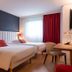L'Amirauté Brest hotel room in Brest with two beds, red curtains, and a desk by the window