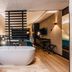 Hotel Hoogeveen bathroom with freestanding tub, walk-in shower and desk in modern suite