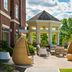 Inn at Bellefield, Hyde Park outdoor patio with wicker chairs, tables, and landscaped seating area