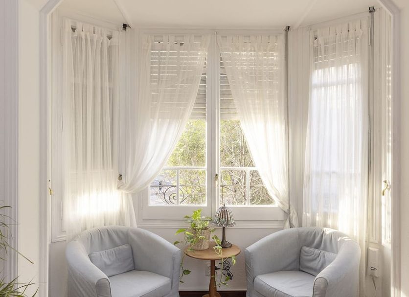 Ally's Guest House Barcelona B&B guest room with two chairs, small table, and sheer curtains in Barcelona