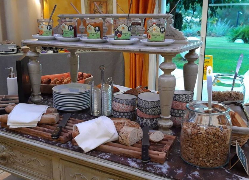 Les Sables D'ocre & Spa breakfast buffet with pastries, cereal jars, plates, and coffee station in Roussillon