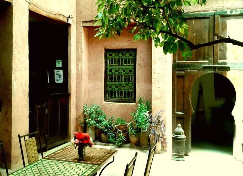 Riad Cascades d'Ouzoud in Ouzoud courtyard with potted plants, table and chairs, and arched doorway