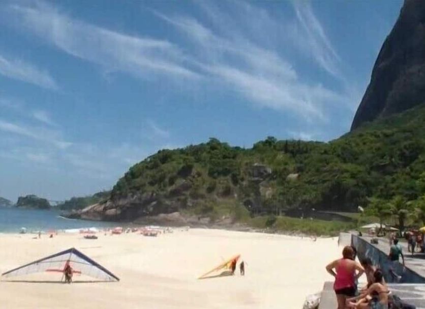Casa São Conrado, Rio de Janeiro: beach view with white sand, umbrellas, and lush hillside coastline