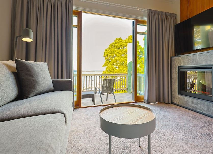 Strahan Village in Strahan room with fireplace, sofa and balcony overlooking trees and water