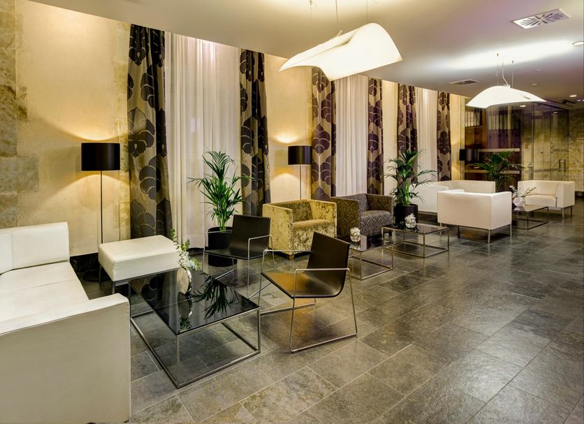 Sercotel Puerta de la Catedral in Salamanca lobby with white seating, glass tables and stone wall