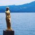 Onsen Yupopo in Semboku with a gold statue by a calm lake and mountain backdrop