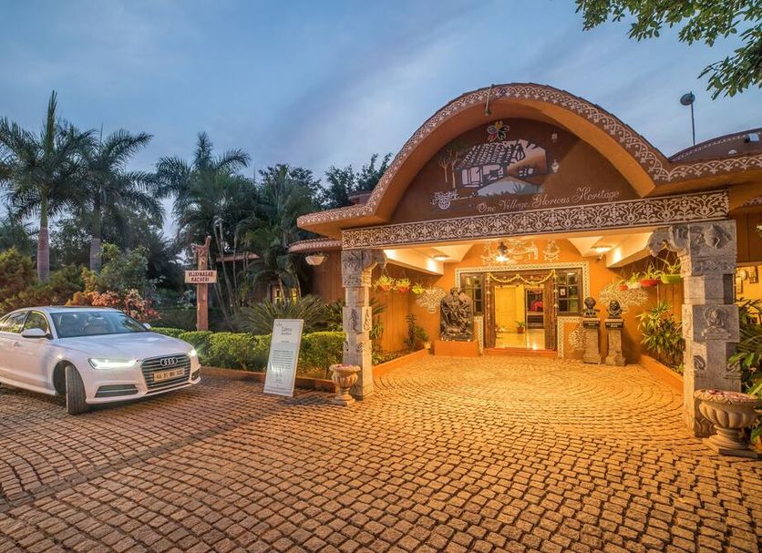 Vijayshree Resort, Hampi in Hosapete: illuminated resort entrance with cobblestone driveway and parked car