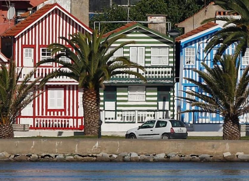 Costa Nova Hotel in Costa Nova with colorful striped beach houses and palm trees along the waterfront