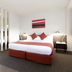 Abode Woden Canberra guest room with queen bed, bedside lamps, mirrored divider and wardrobe